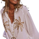 White embroidered shirt with palm tree designs on a white background