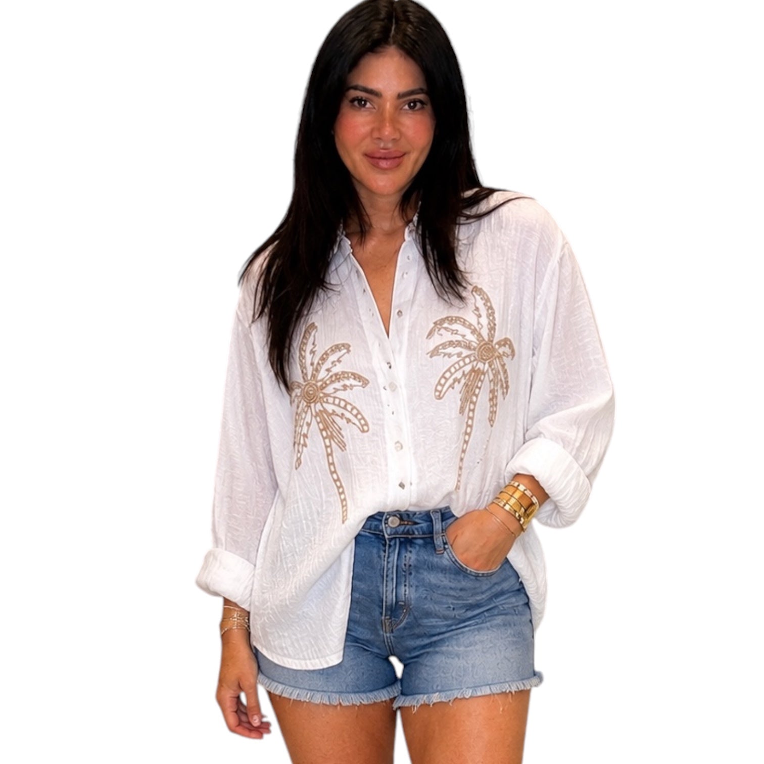 Woman wearing a white blouse with palm tree designs and denim shorts on a white background