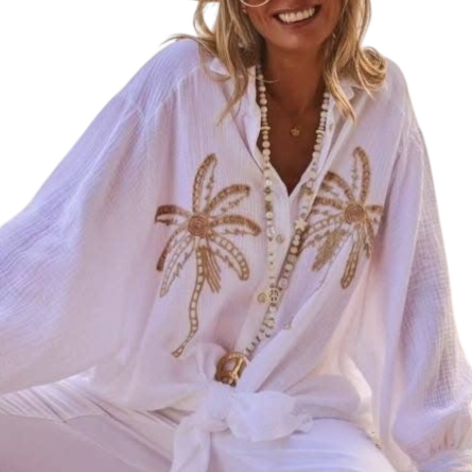 Woman wearing a white cover-up with gold palm tree designs on a white background