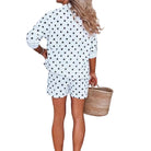 Woman in a polka dot outfit standing in a room with a plant and a basket.