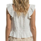 White sleeveless top with ruffled shoulders worn by a person on a white background