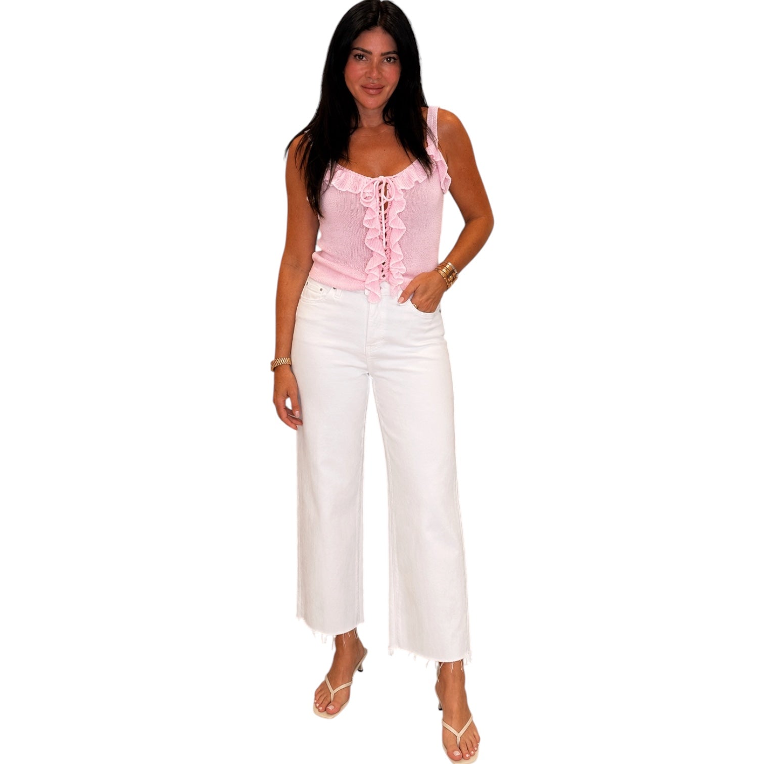 Woman wearing a pink top and white pants on a white background
