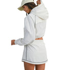 Woman wearing a white outfit with black trim on a white background