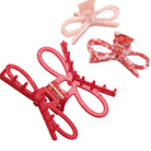 Red hair clip held by a hand with blurred decorative hair clips in the background