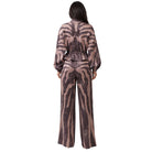 A woman viewed from the back wearing a long-sleeve jumpsuit with a brown and beige zebra-like animal print, set against a plain white background.
