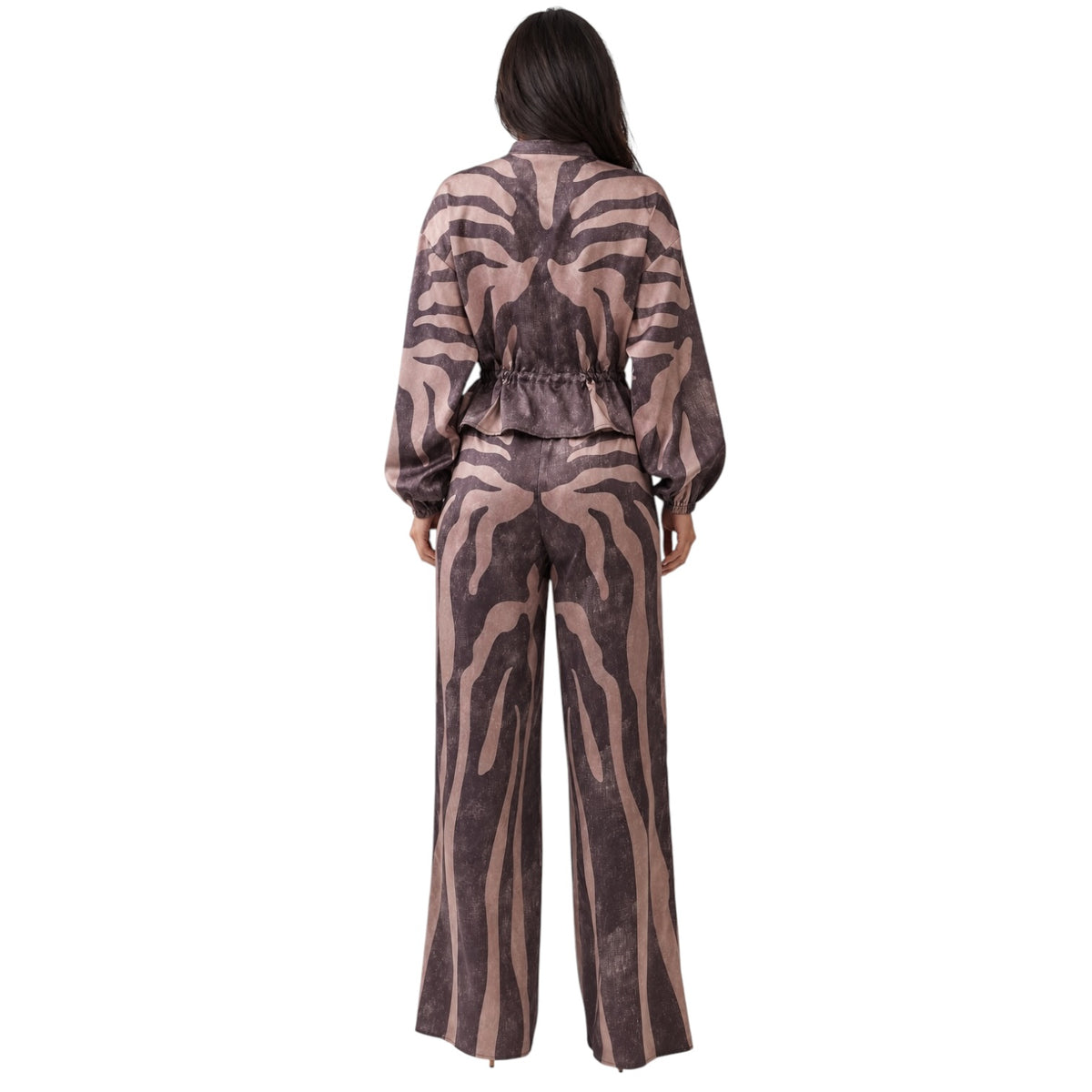 A woman viewed from the back wearing a long-sleeve jumpsuit with a brown and beige zebra-like animal print, set against a plain white background.