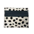 A square card holder or wallet featuring a black and white cowhide dalmatian spot pattern with a wide black leather band across the center, shown on a plain white background.