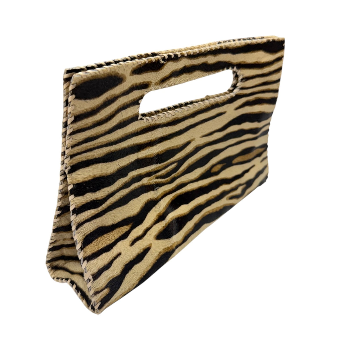 A zebra-print handbag made of textured cowhide with a cutout handle, shown on a plain white background.