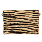 A zebra-print handbag made from cowhide, featuring a flap closure with whipstitching and gold-tone metal hardware on a white background.