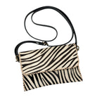 A small crossbody handbag with a black and beige zebra print pattern, featuring a black leather strap and gold-tone hardware, shown on a plain white background.