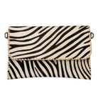 A zebra-print handbag with black and cream stripes, featuring a flap closure, whipstitched edges, and brass-tone hardware on a plain white background.