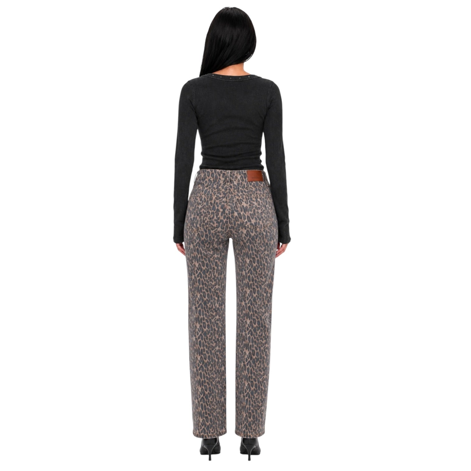 A woman shown from the back wearing leopard-print trousers and a black long-sleeve top against a plain white background.