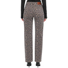 A pair of high-waisted leopard print trousers shown from the back on a model, paired with a black long-sleeve top and black heels against a plain white background.