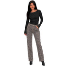 A woman modeling a black long-sleeve top and high-waisted, straight-leg trousers with a brown and beige leopard print, set against a plain white background.