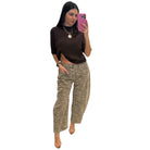 Woman taking a selfie wearing a brown top and zebra print pants on a white background