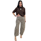 Woman wearing a brown top and zebra print pants on a white background