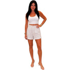 Woman wearing a white sleeveless top and shorts on a white background