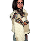 Person wearing a textured white jacket with floral pattern, and jeans indoors.