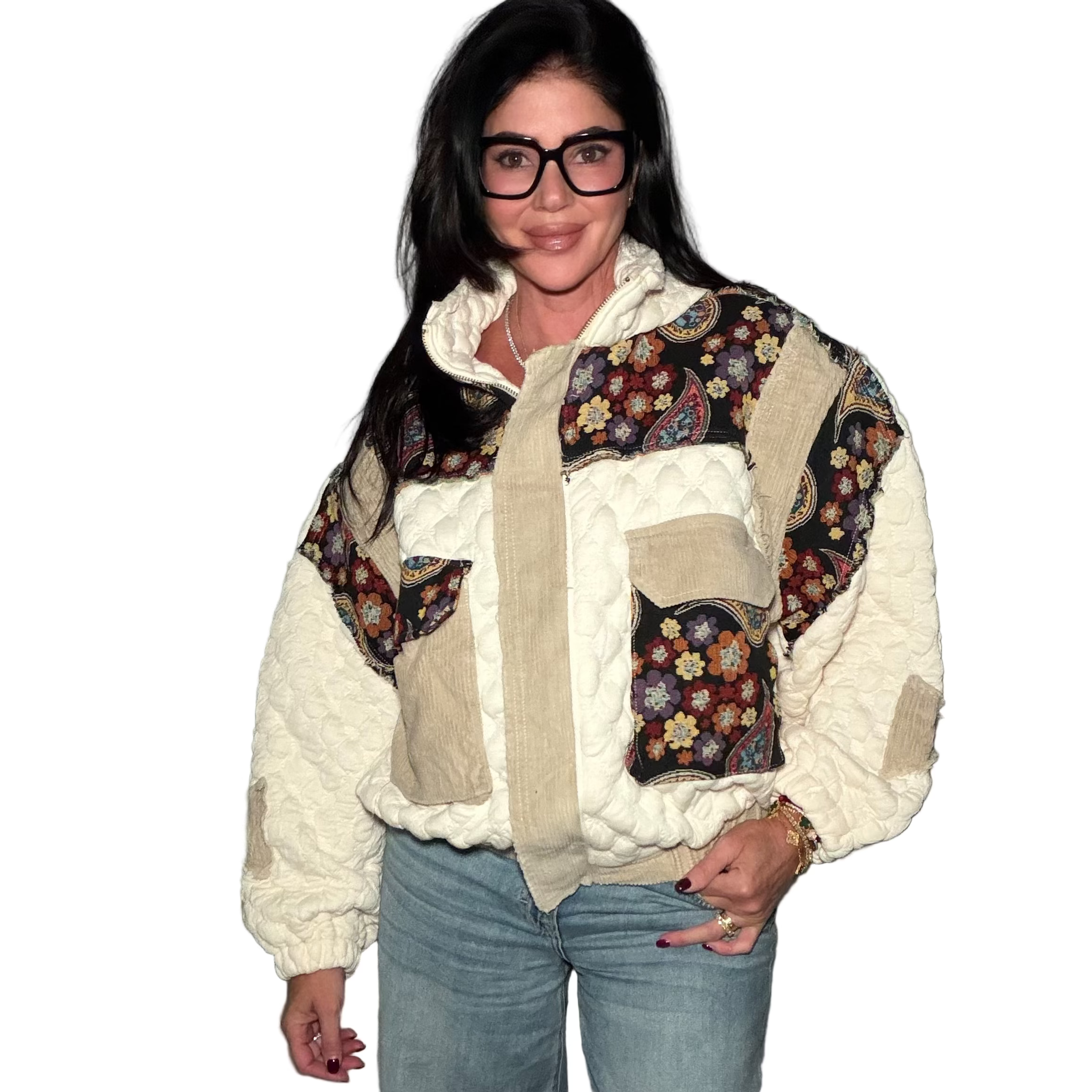 Person wearing a patchwork jacket with floral patterns and blue jeans indoors.