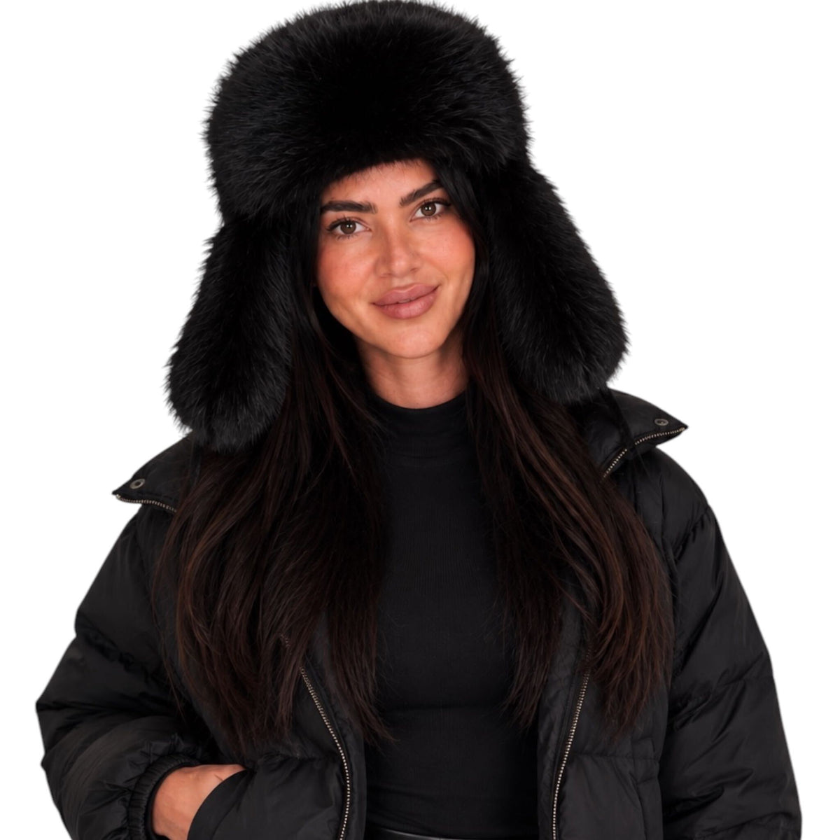 A woman wearing a black fur ushanka hat with ear flaps and a black puffer jacket, shown against a plain white background.