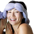 Woman wearing a light purple eye mask with a white background