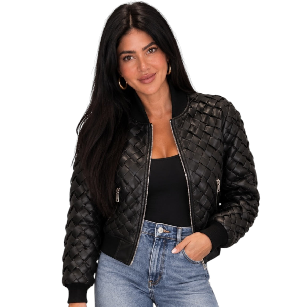 A woman modeling a black quilted faux-leather bomber jacket with silver zippers, worn over a black top and blue jeans against a plain white background.