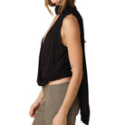 Woman wearing a black sleeveless top and beige pants on a white background