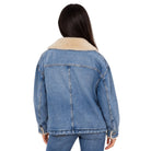 A woman viewed from the back wearing a light blue denim jacket with a beige shearling-style collar, paired with blue jeans, against a plain white background.