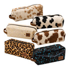 Six zippered pouches in different animal-print and speckled designs, arranged on a plain white background. The pouches include cow print, leopard print, and blue-tinted black splatter patterns, each with a small brown leather patch label.