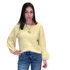 Woman wearing a yellow sweater and blue jeans on a white background