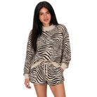A woman modeling a beige and black zebra-print long-sleeve knit romper with a drawstring waist, set against a plain white background.
