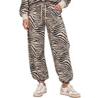 A person wearing loose zebra-print jogger pants with a drawstring waist, shown from the waist down against a plain white background.