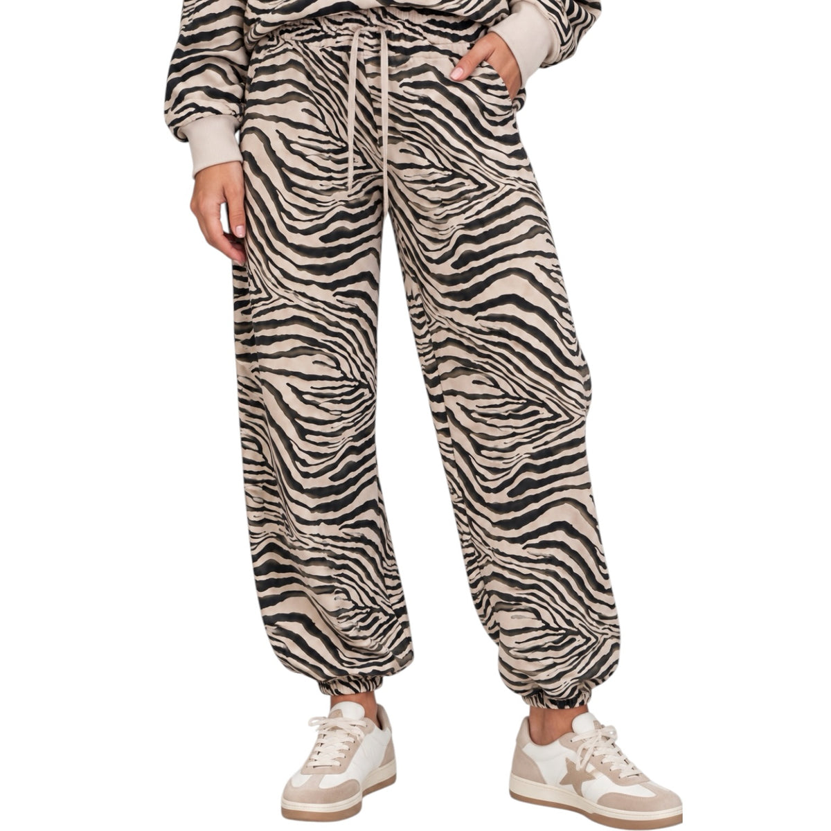 A person wearing loose zebra-print jogger pants with a drawstring waist, shown from the waist down against a plain white background.
