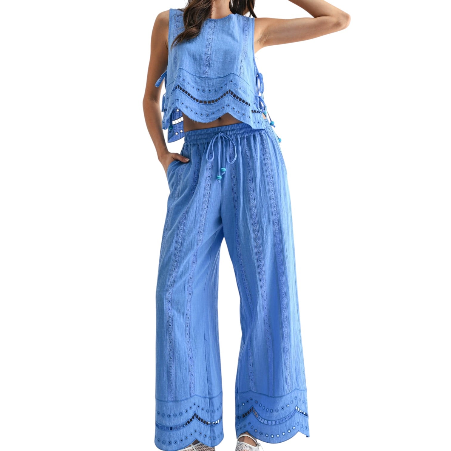 Woman wearing a blue embroidered top and wide-leg pants on a white background
