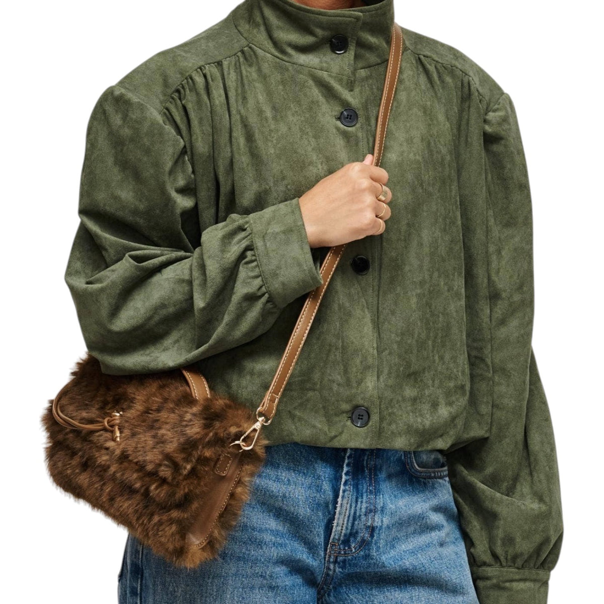 A person wearing an olive green corduroy jacket and blue jeans, carrying a brown faux-fur crossbody bag with a tan strap.