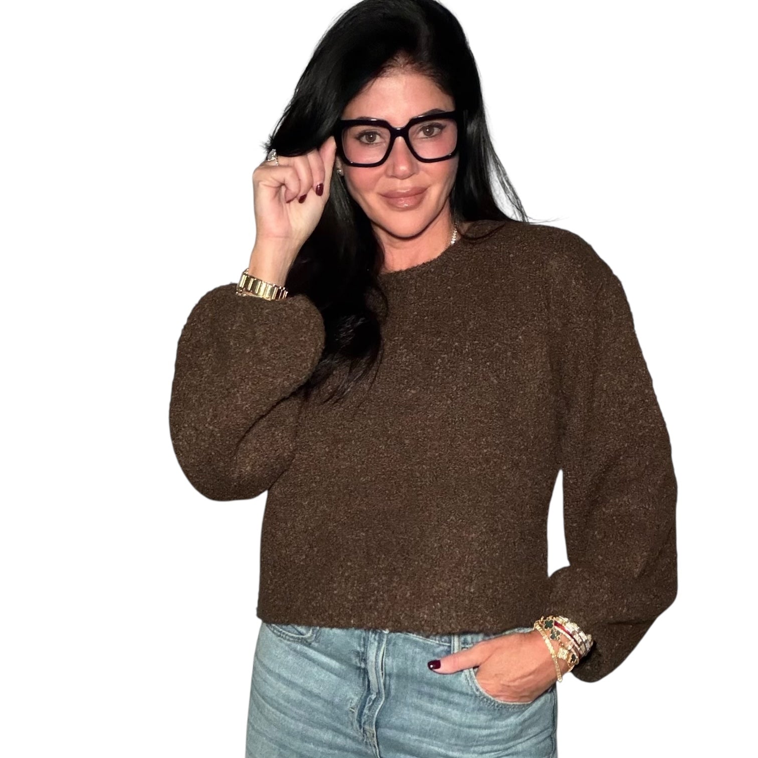 Woman wearing a brown sweater and light blue jeans on a white background