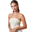 Model wearing a cream crochet flyaway tube top, showcasing intricate detailing and a modern silhouette, paired with light bottoms.