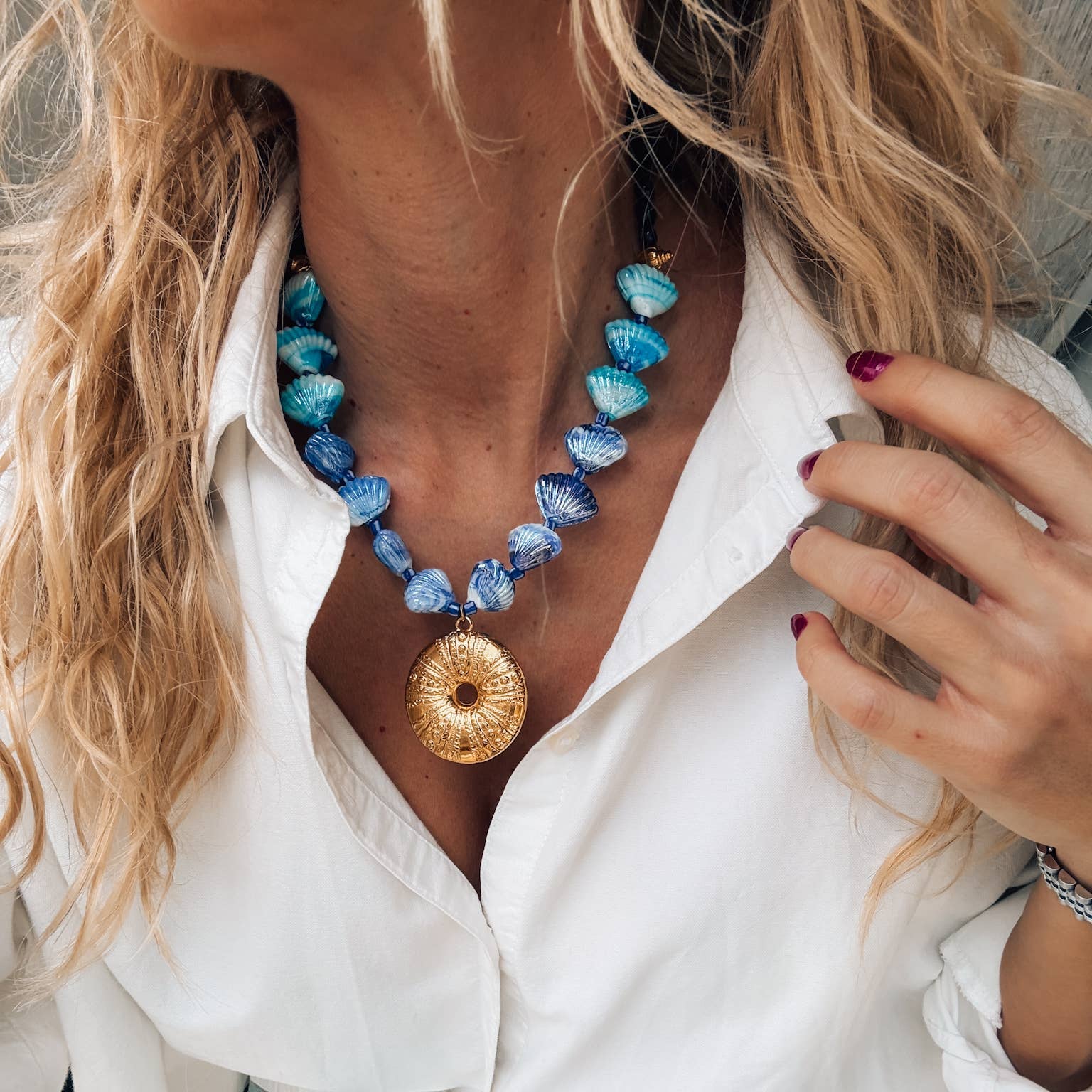 Gold large urchin statement necklace with blue scallop shells, perfect for summer beach outfits.