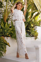 Model showcasing the Floral Lace Belted Pants Set in white, featuring crochet lace details, in a lush garden setting.