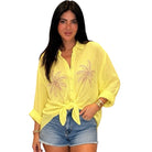 Woman wearing a yellow embroidered shirt and denim shorts on a white background